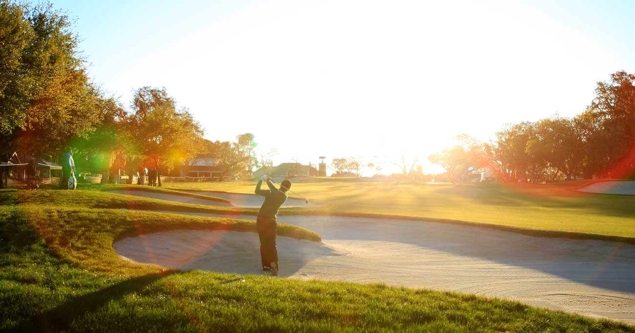 golfer splashes sand trap
