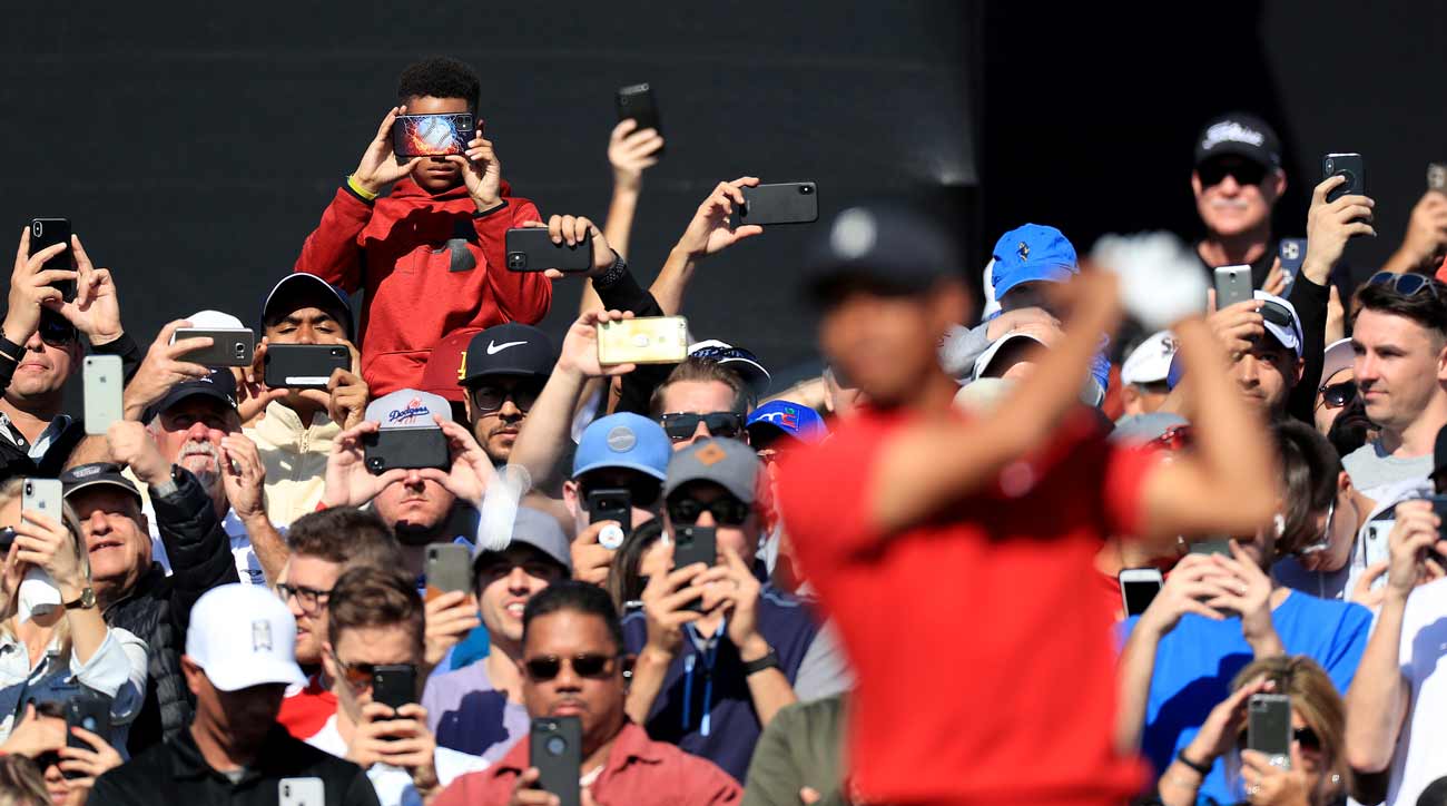 Fans photograph Tiger Woods playing golf