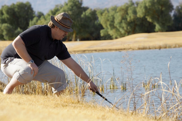 Man Looking For Golf Ball in Pond