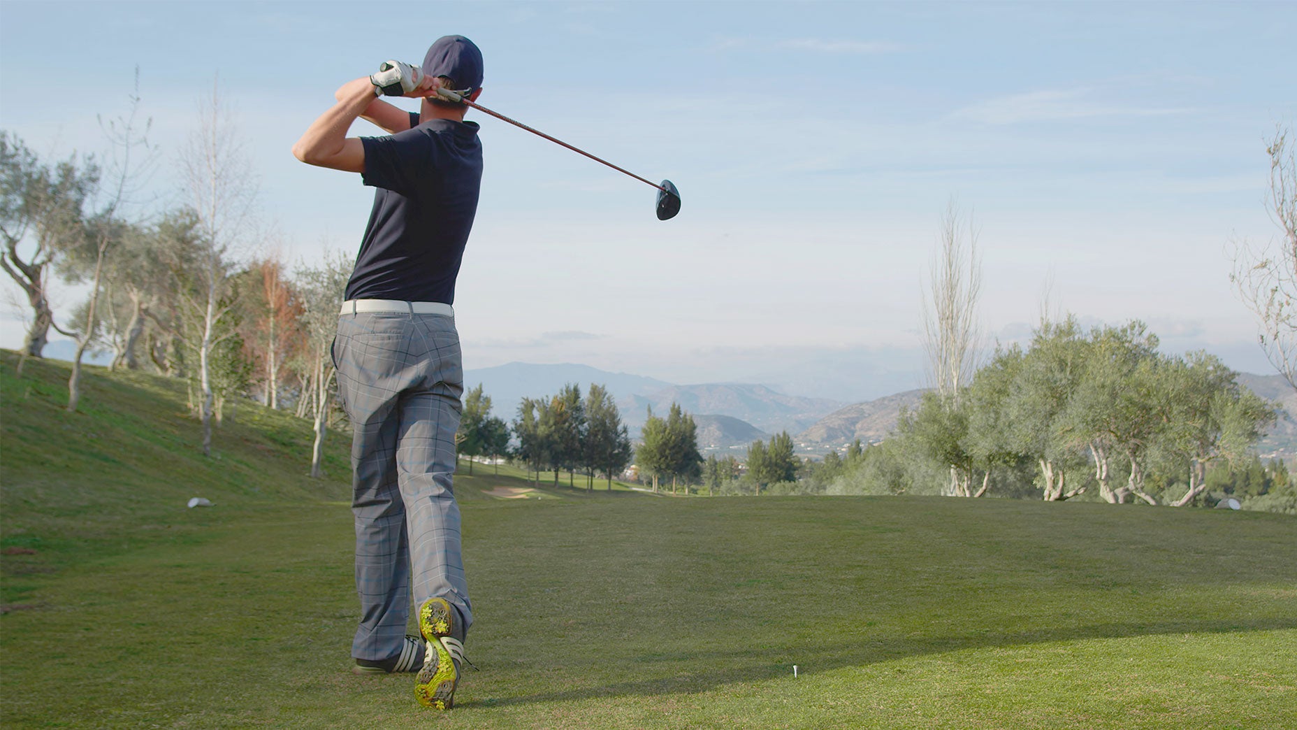 A golfer takes a swing.