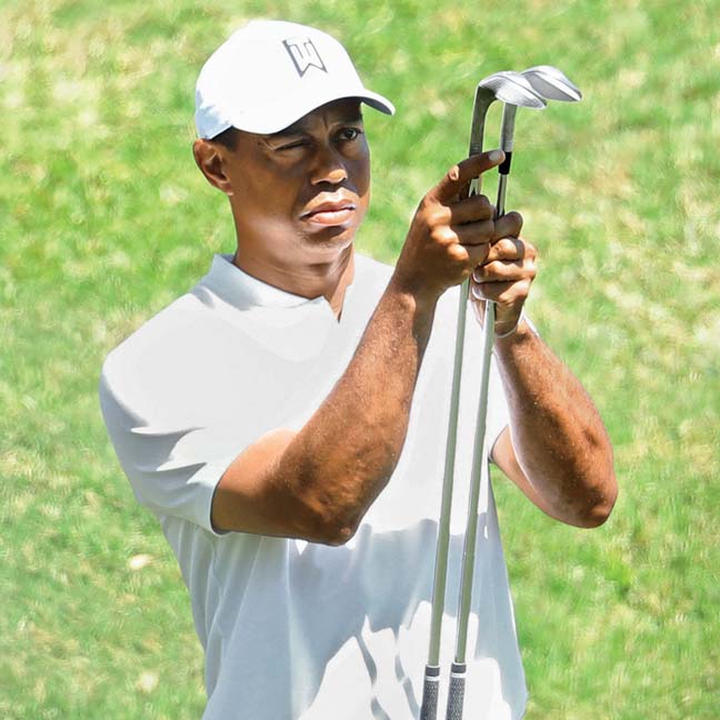 Tiger Woods looks at golf iron heads.