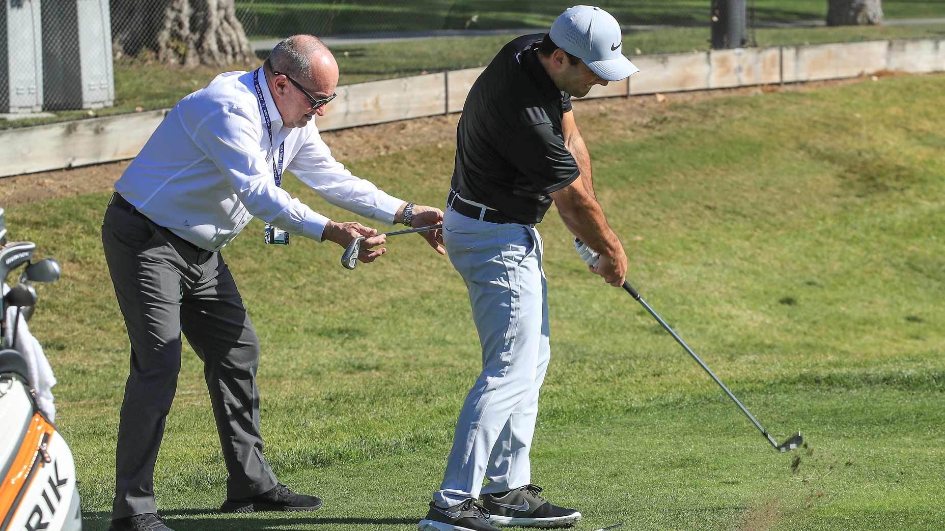 coach helps golfer on range