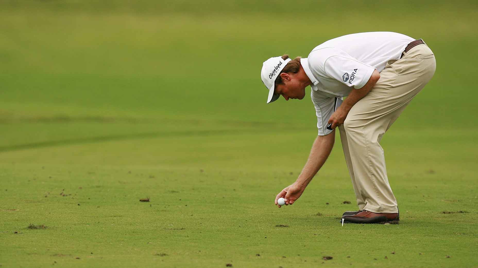 Golfer replacing ball in fairway