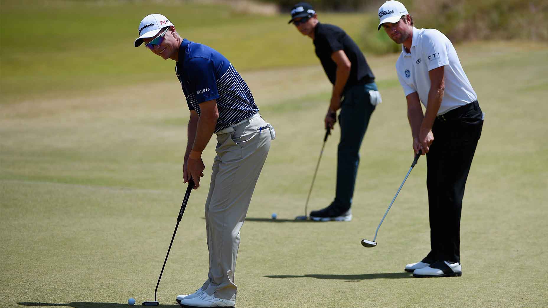 three golfers putting
