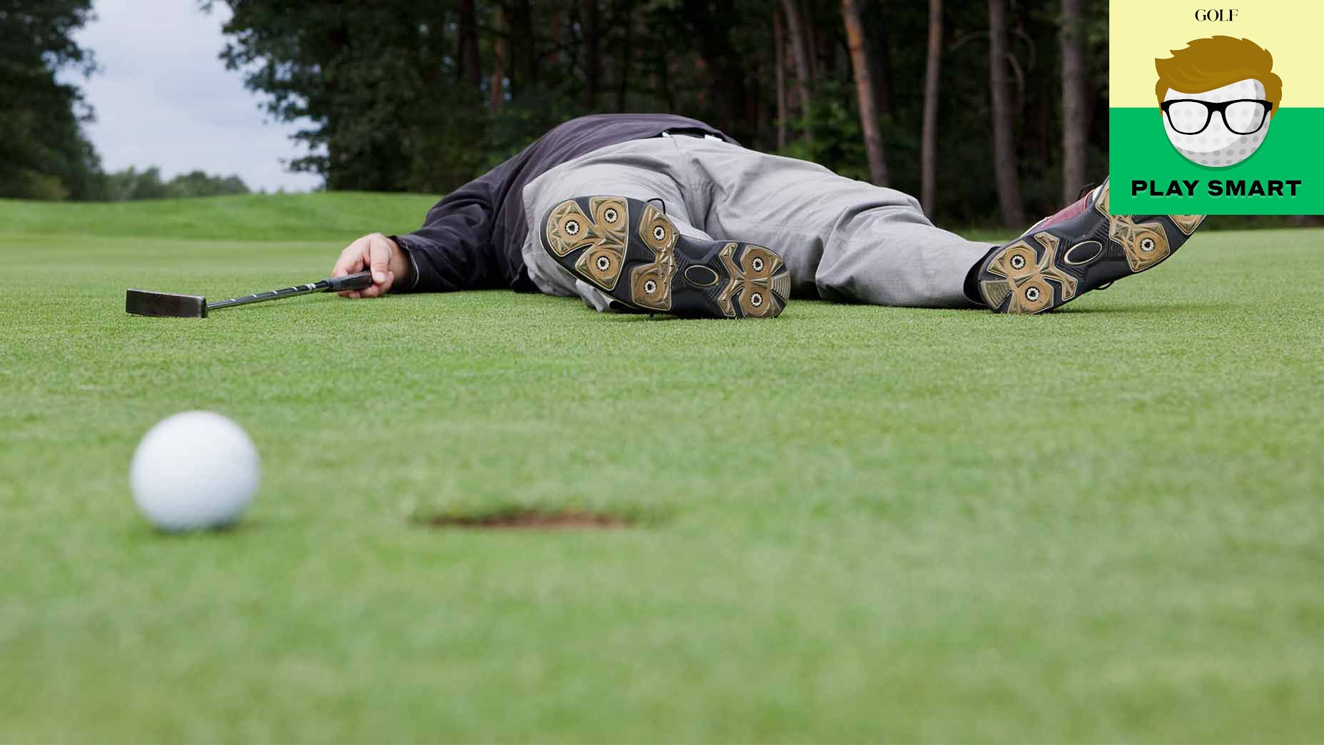 golfer lying down on green with ball near hole in foreground