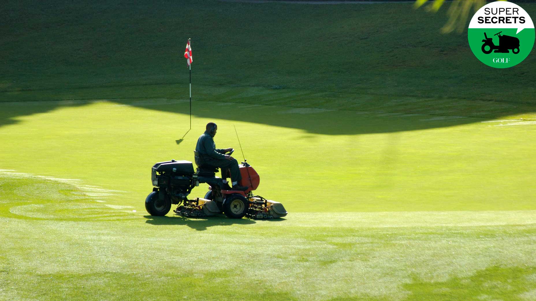 A man mows a golf green.