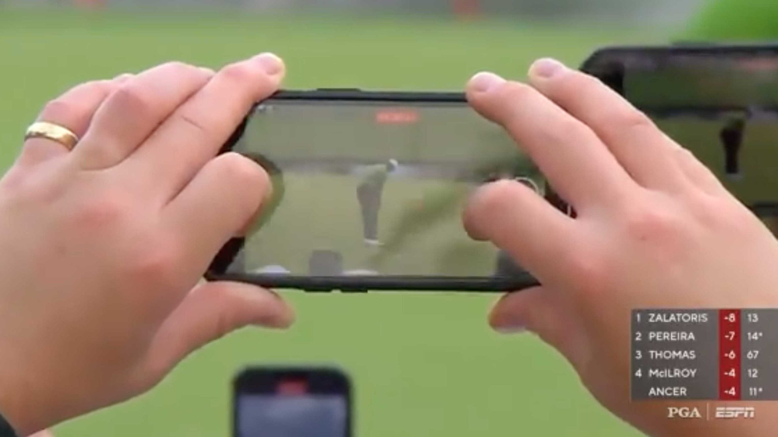 An ESPN camera gets a shot of a Tiger Woods putt through the phone of a fan.