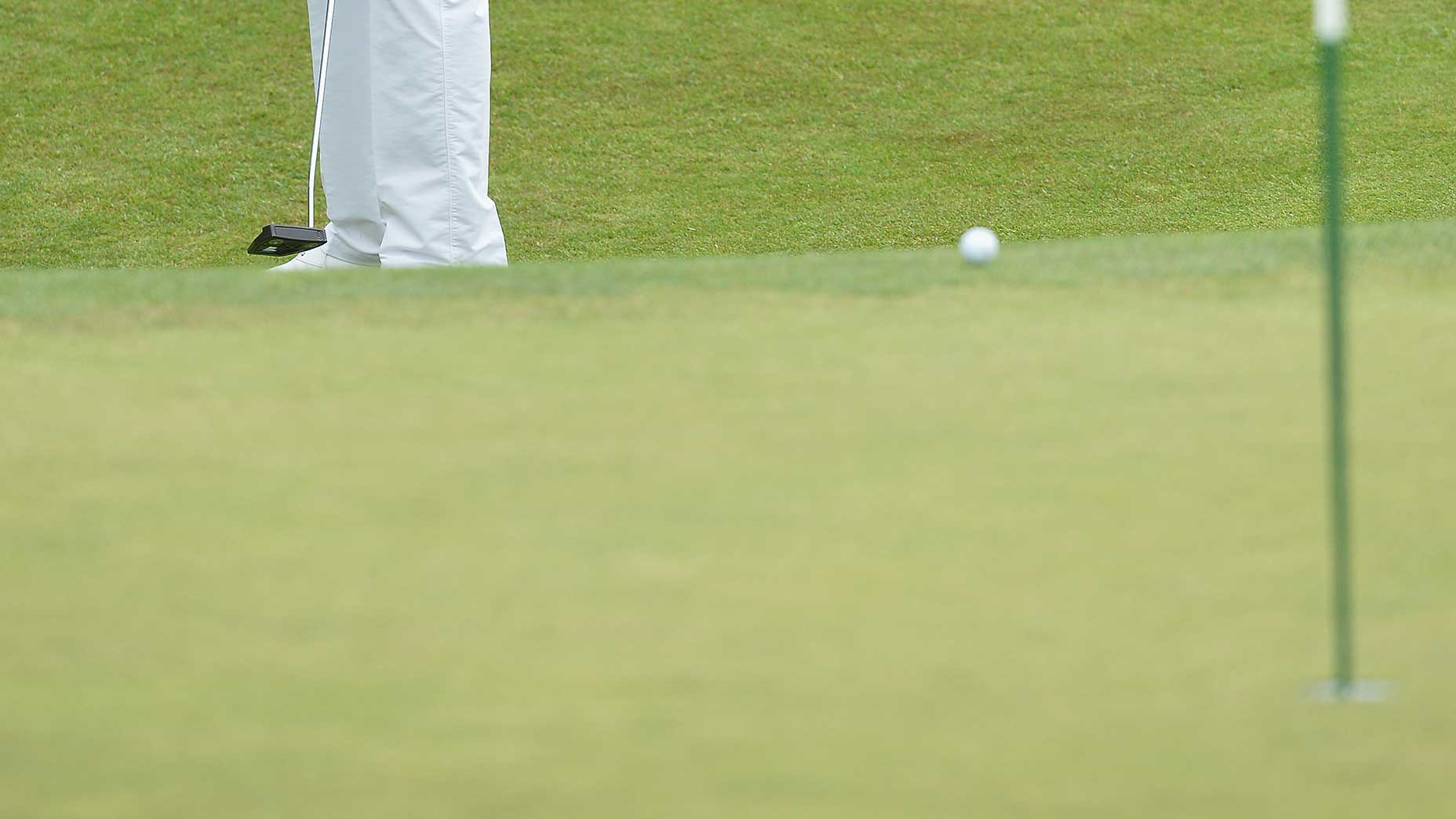 a golfer putts from off the green.
