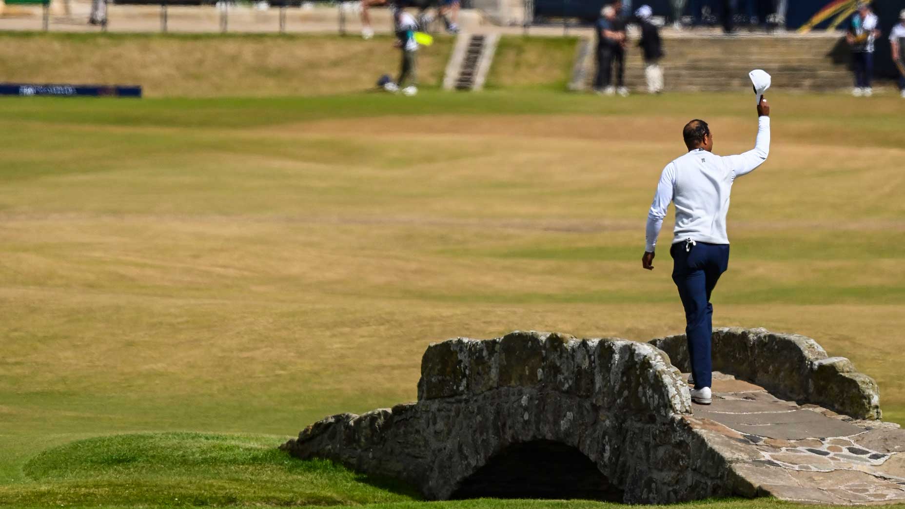 Tiger Woods waves his hat to fans as he walks across the Swilken Bridge on the 18th hole during the second round of The 150th Open Championship on The Old Course at St Andrews on July 15, 2022 in St. Andrews, Scotland.