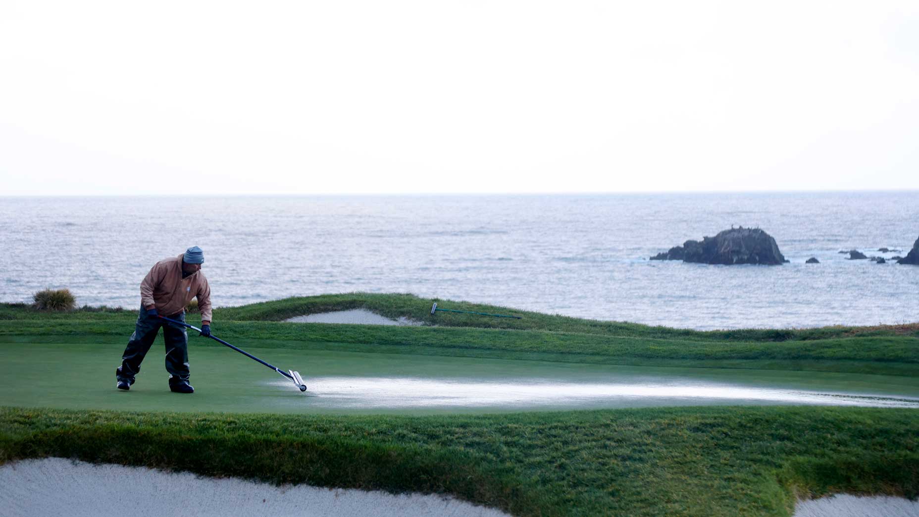 Grounds crew attempt to dry the green on the fifth hole during a continuation of the third round of the AT&T Pebble Beach Pro-Am at Pebble Beach Golf Links on February 05, 2023 in Pebble Beach, California.