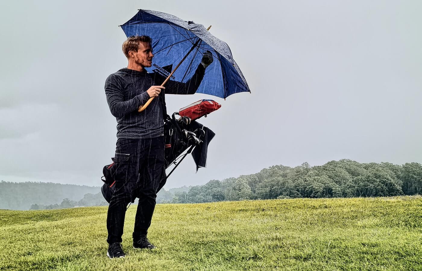 Golfer in the rain holding an umbrella