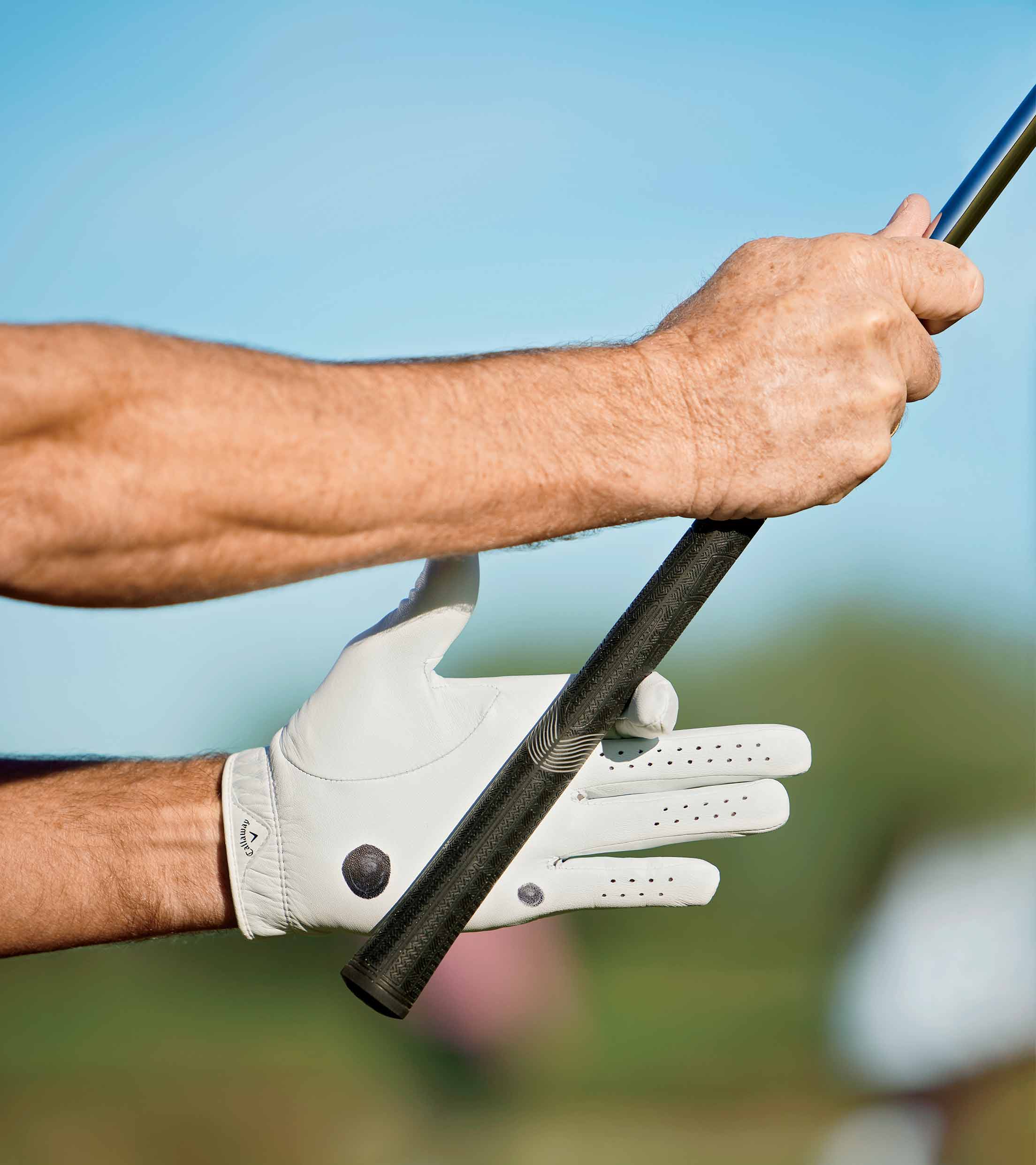 one hand on a golf club