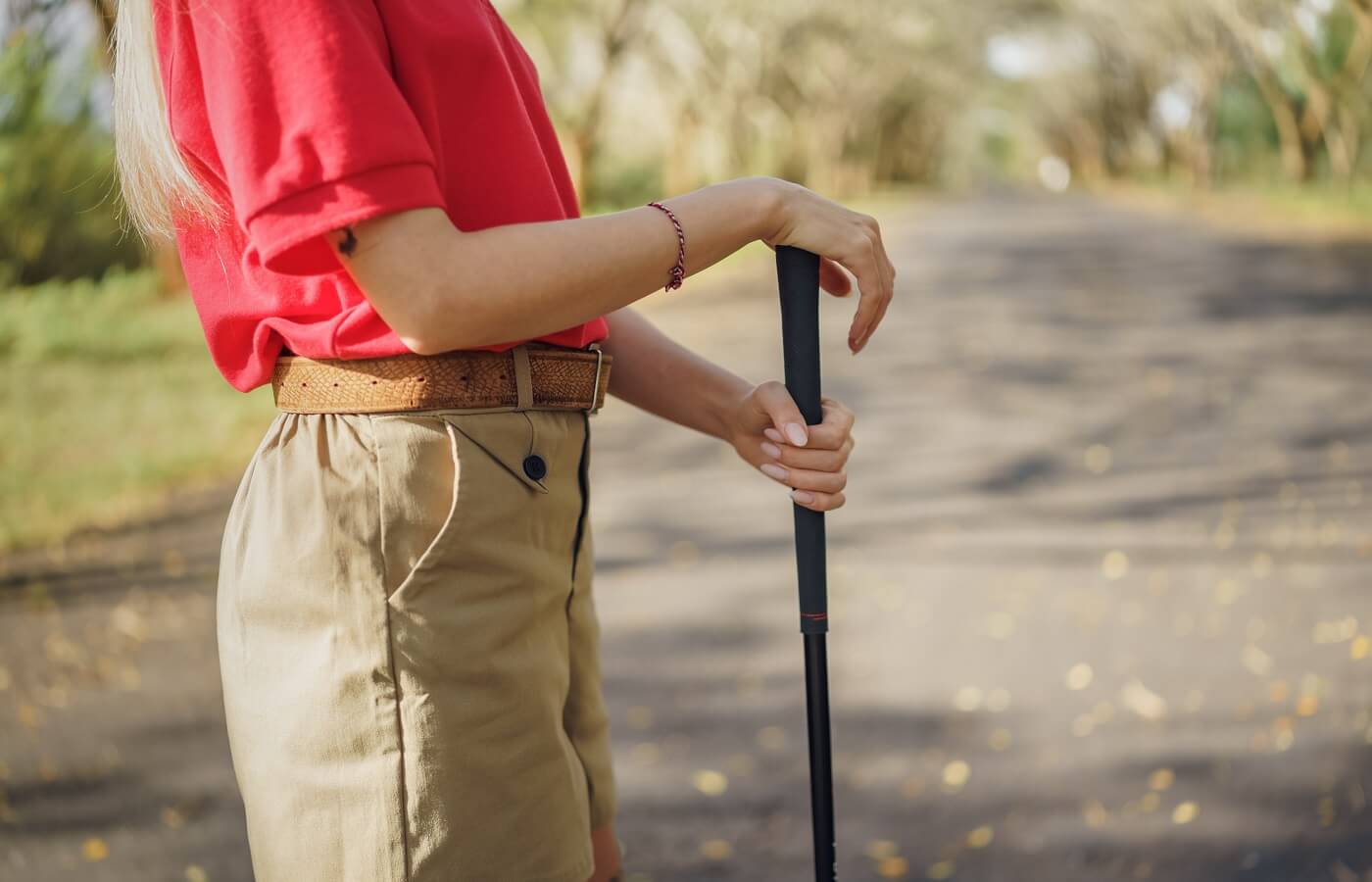 Woman golfer in red shirt and khaki shorts wearing a belt