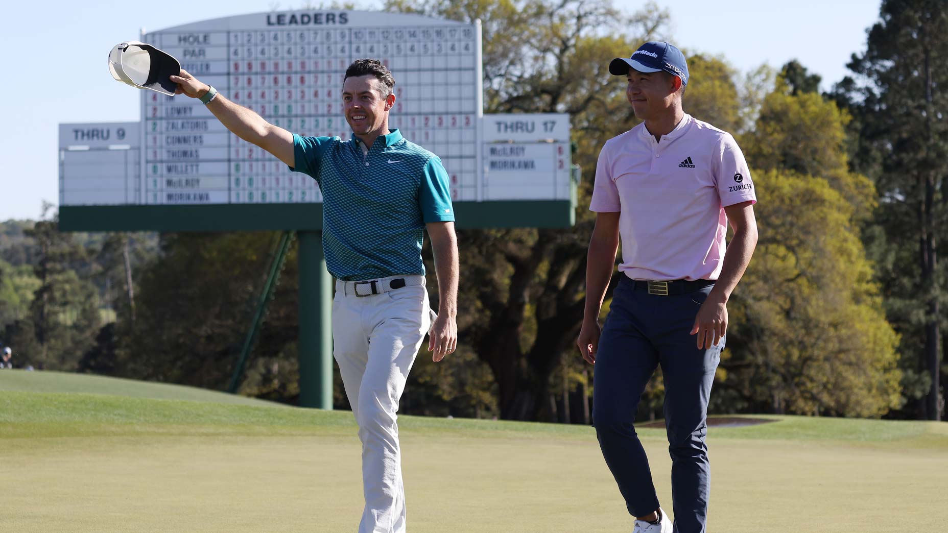 Rory McIlroy of Northern Ireland (L) and Collin Morikawa acknowledge the fans as they walk off the 18th green after finishing their round during the final round of the Masters at Augusta National Golf Club on April 10, 2022 in Augusta, Georgia.