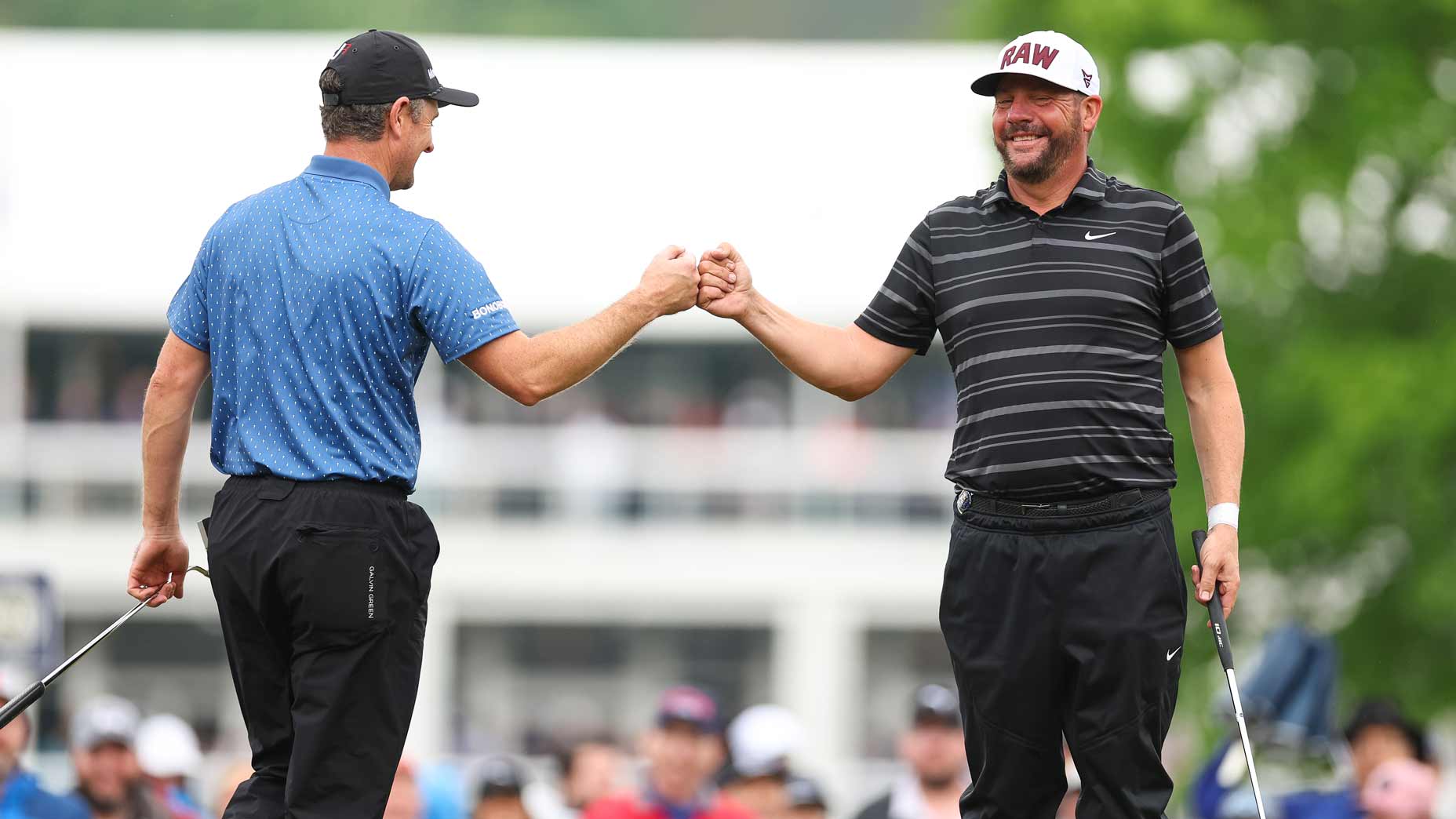 Justin Rose fist bumps Michael Block of the Corebridge Financial PGA Team to his putt on the eighth hole during the third round of the PGA Championship at Oak Hill Country Club on May 20, 2023 in Rochester, New York.