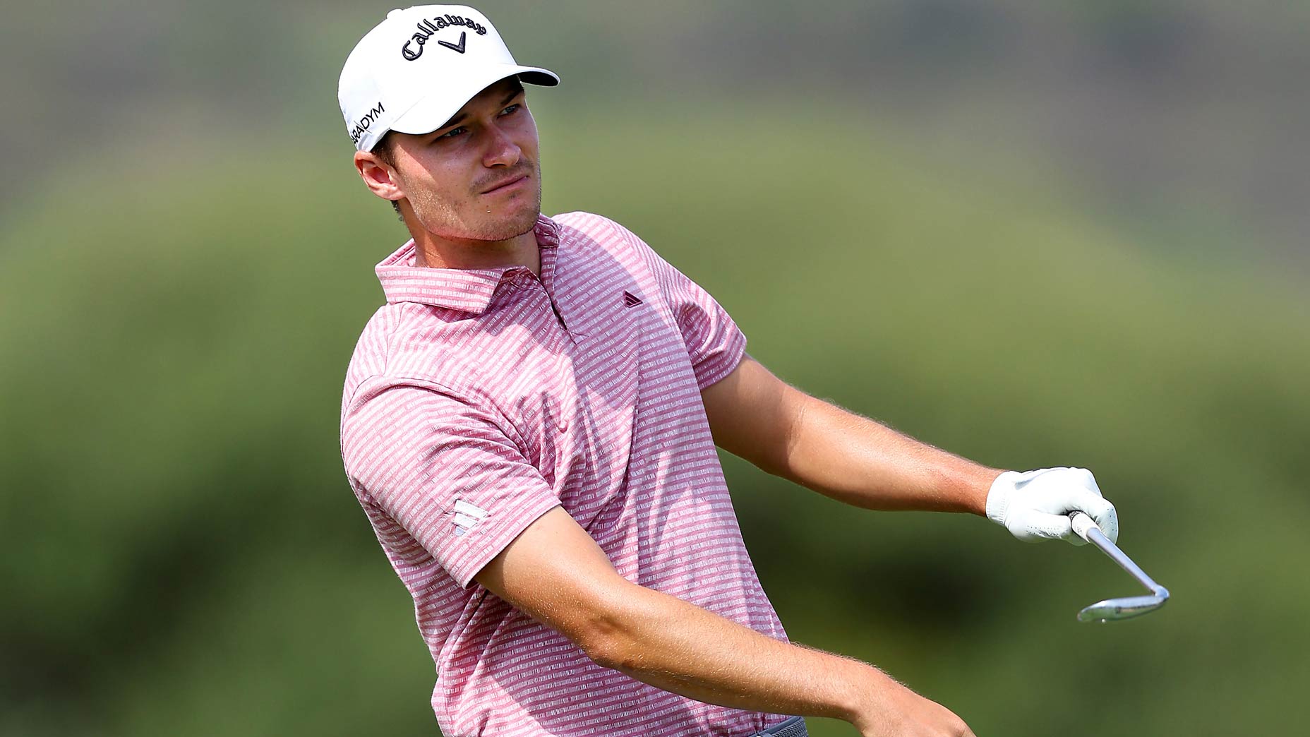 Rasmus Hojgaard, a golfer in a pink shirt, swinging a golf club.