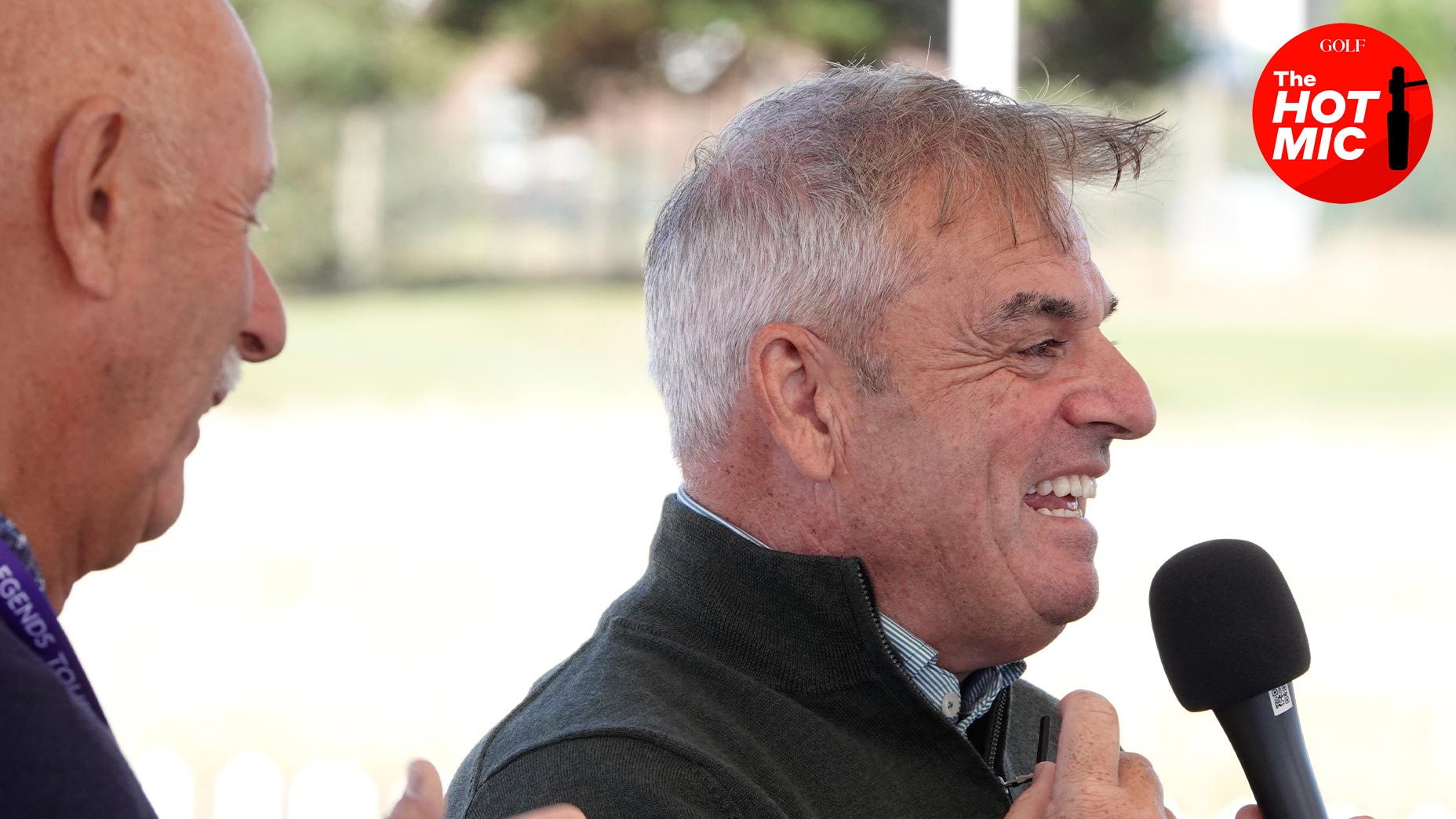 paul mcginley smiles while holding microphone from european tour event