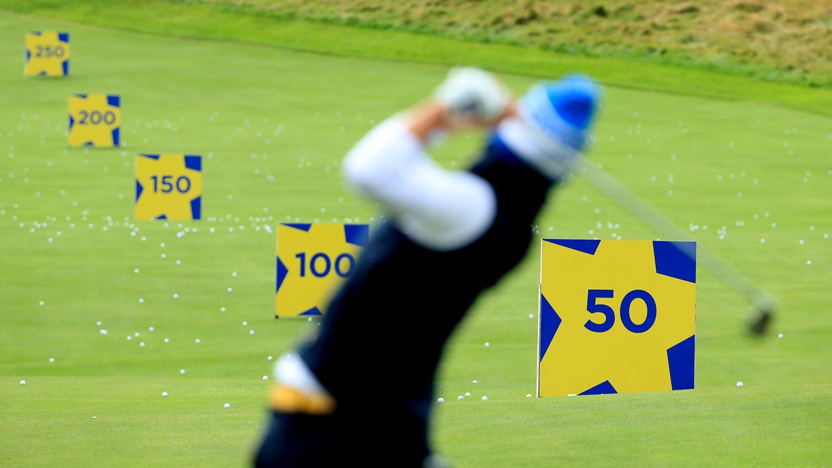 golfer hitting balls on range with yardage markers