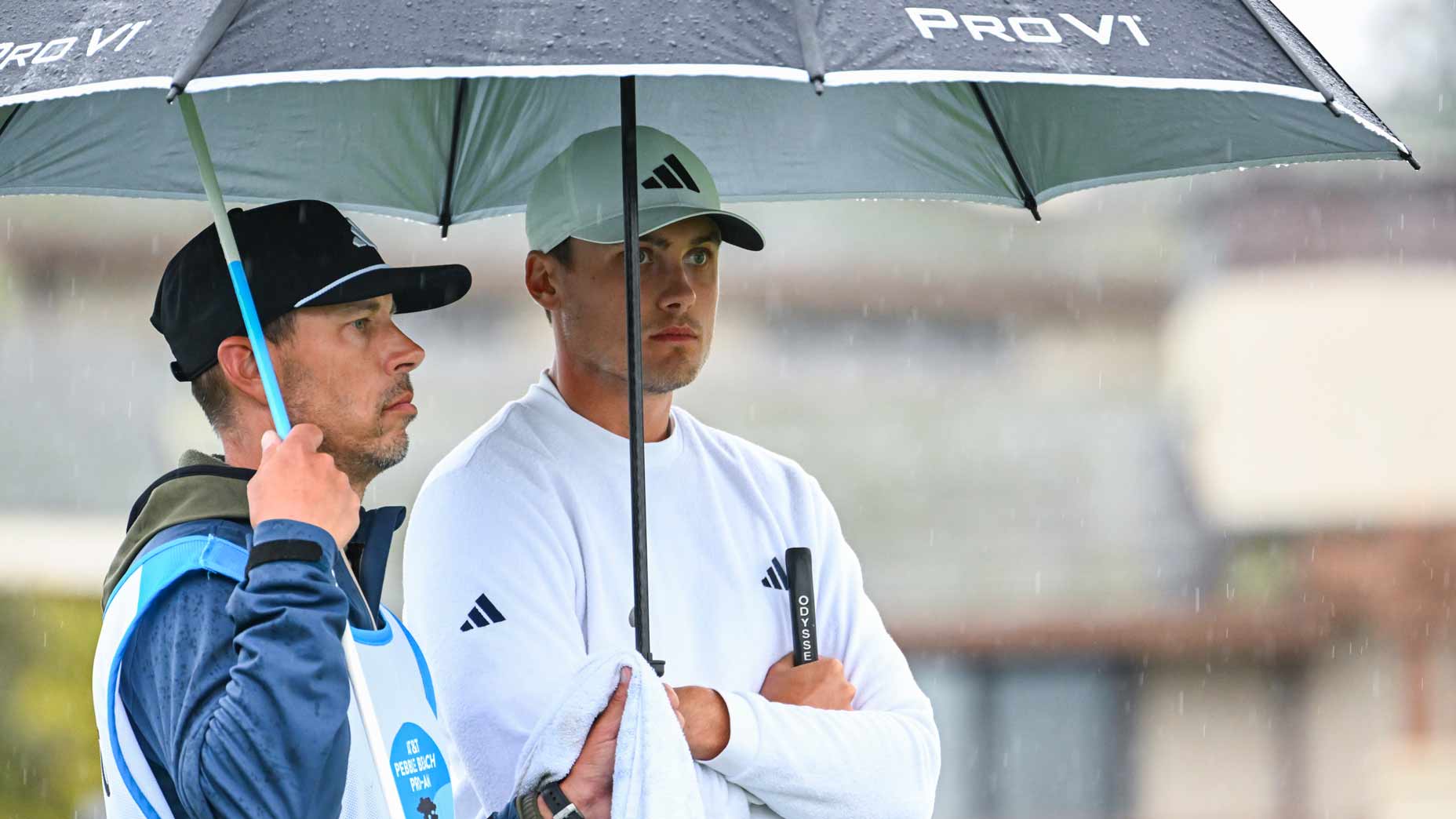 Ludvig Aberg waits in the rain with an umbrella.