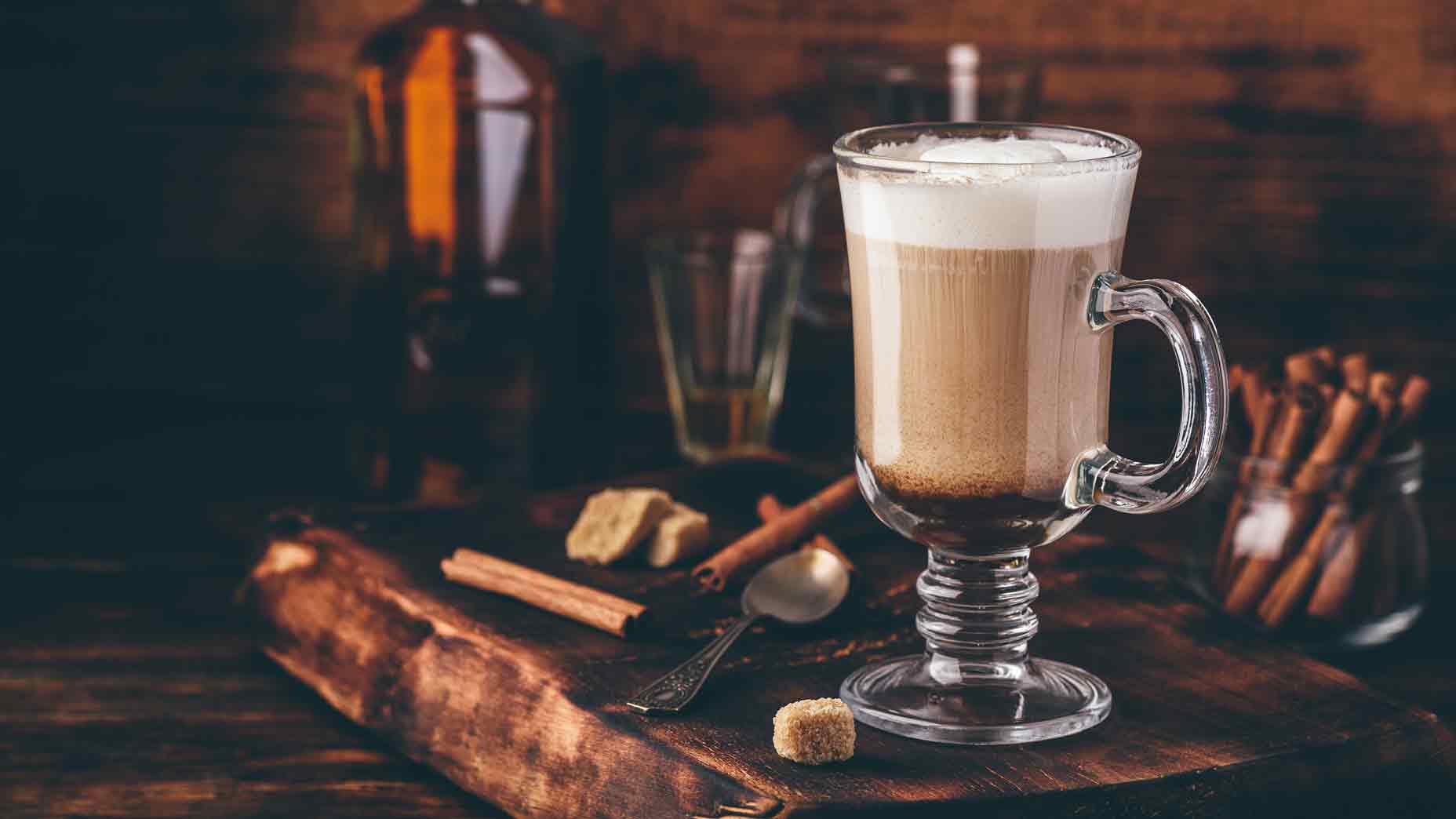 Coffee with Irish whiskey and whipped cream in glass on rustic wooden surface