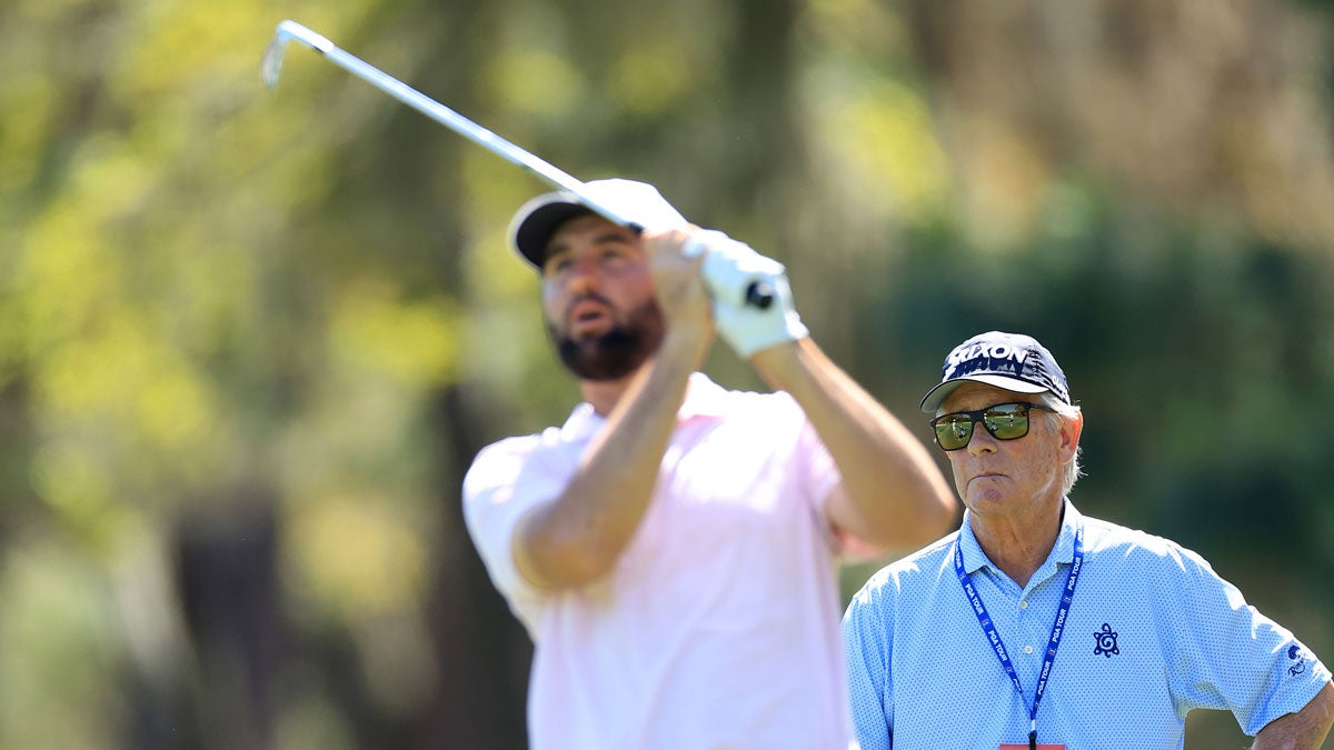 Scottie Scheffler of the United States plays a shot watched by his coach Randy Smith on the 15th hole prior to THE PLAYERS Championship on the Stadium Course at TPC Sawgrass