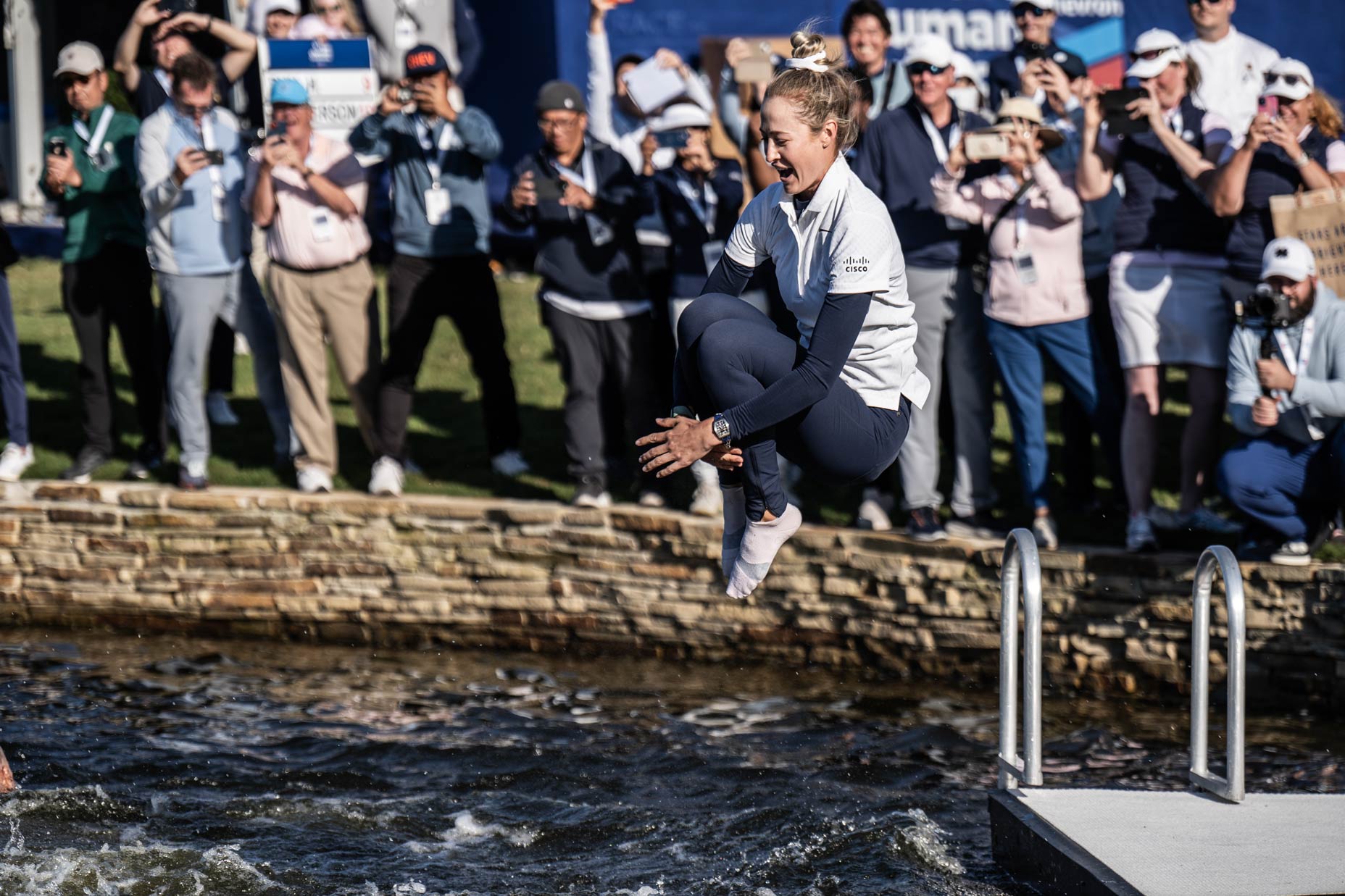 Nelly Korda jumps in a pond.