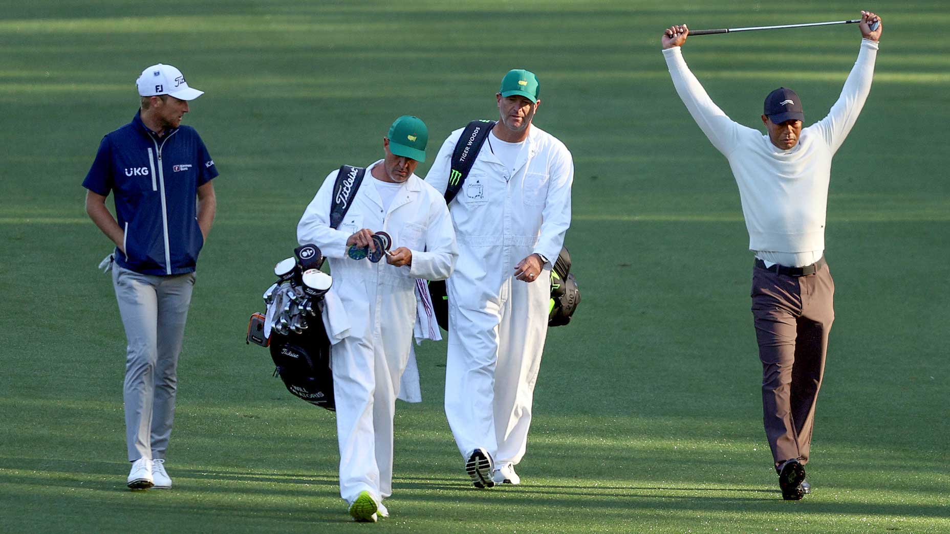 Tiger Woods, Will Zalatoris, and their caddies walk down the fairway.