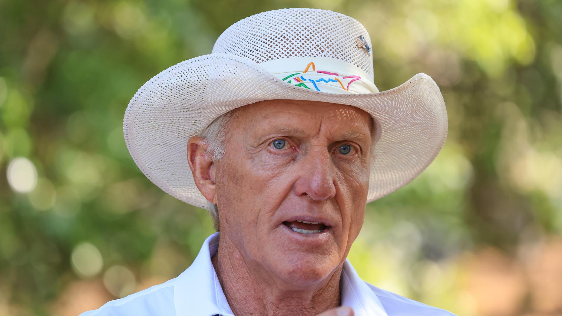 greg norman speaks at masters tournament in white logoed safari hat