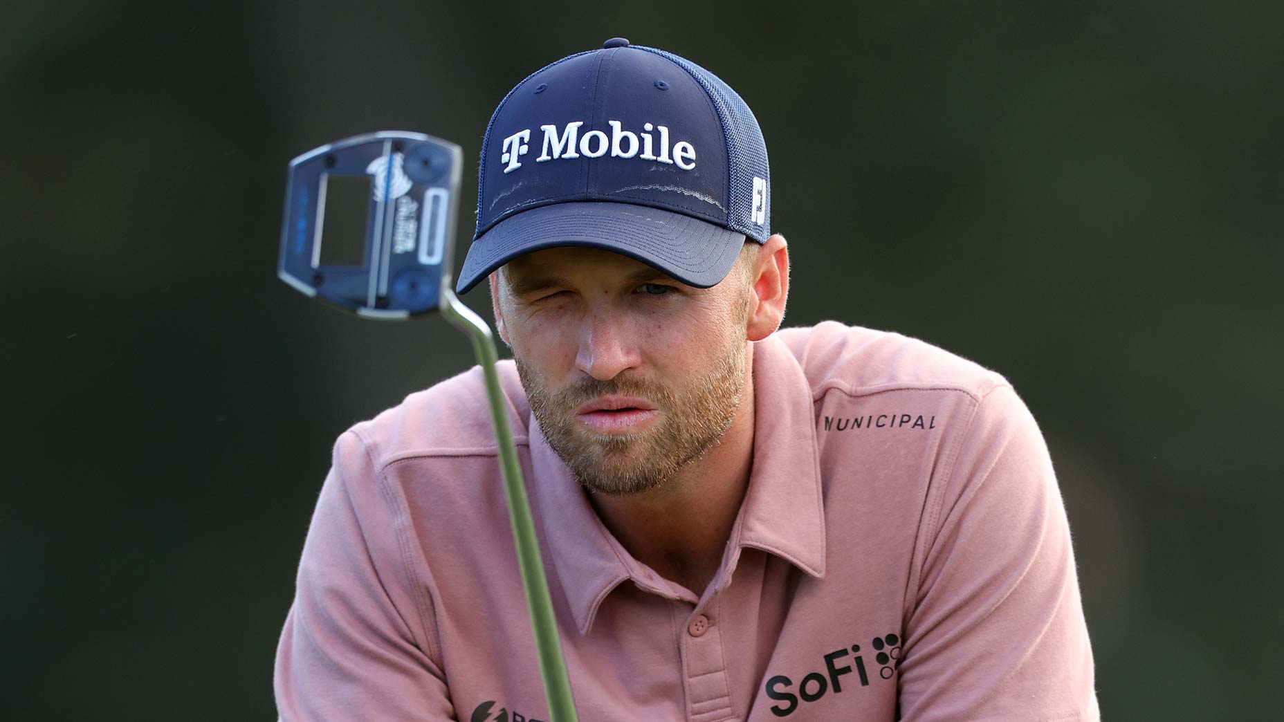 Pro golfer Wyndham Clark crouches to read putt at 2024 Masters