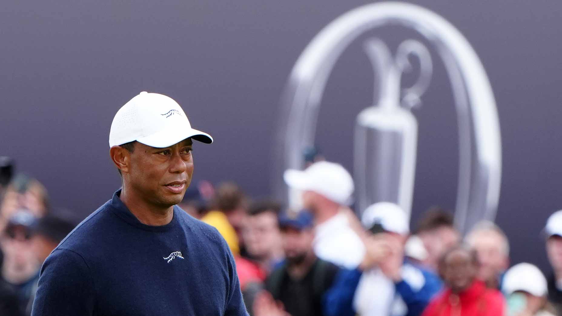 tiger woods stares at the open in navy crewneck and white hat at the open at royal troon