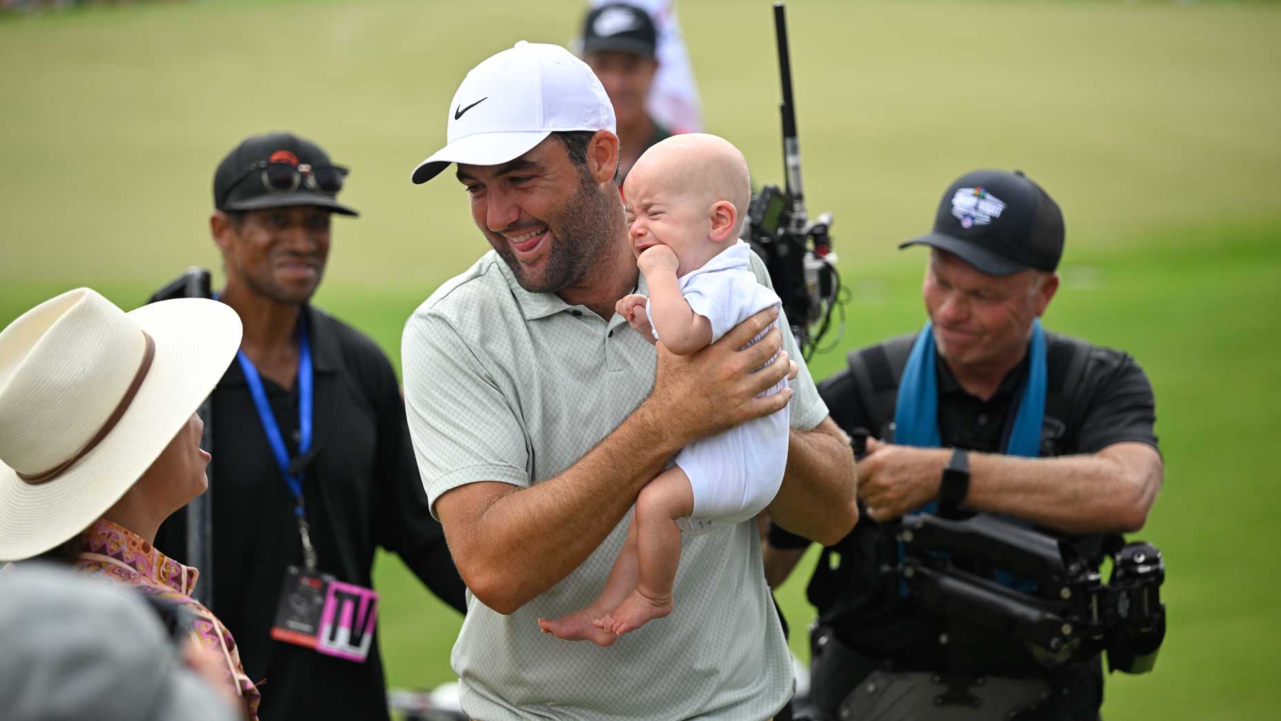 PGA Tour player Scottie Scheffler holds his son, Bennett Scheffler, on the 18th green during the final round of the 2024 Tour Championship at East Lake Golf Club.