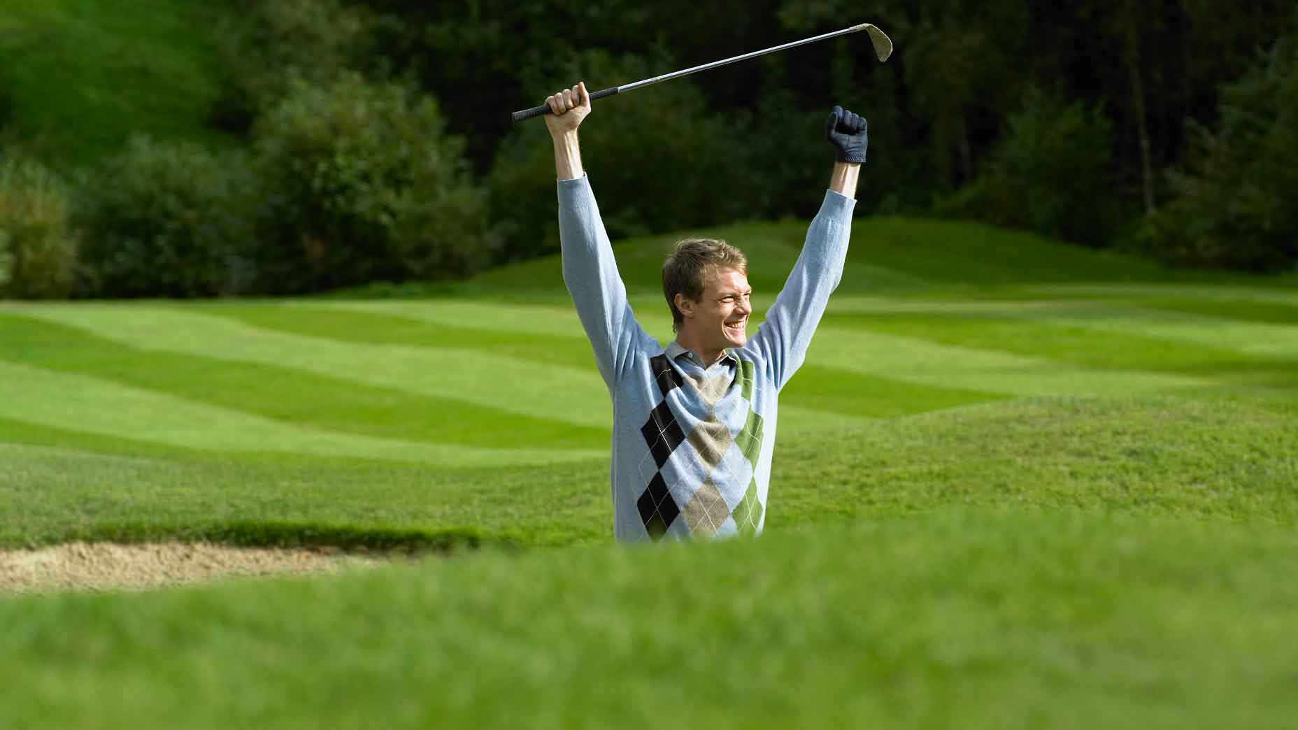 golfer lifts his arms in celebration