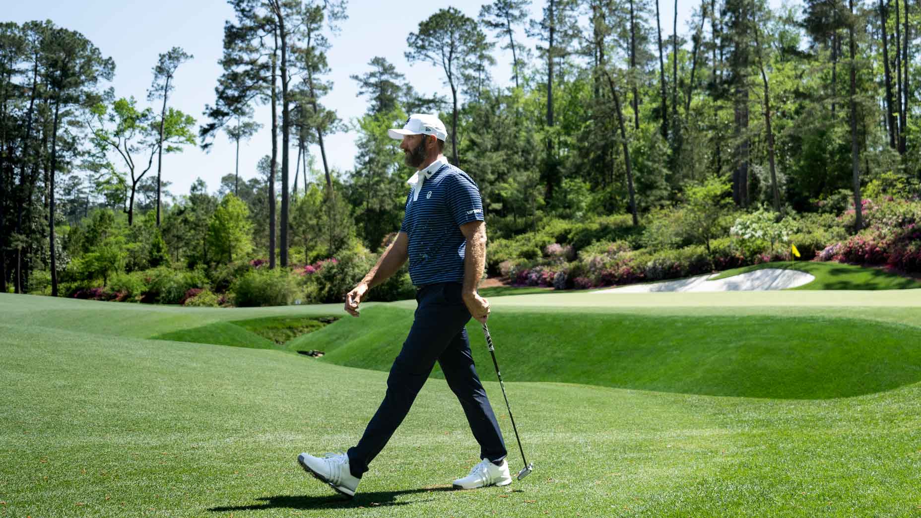 dustin johnson walks at augusta national in front of 13th green at the Masters.