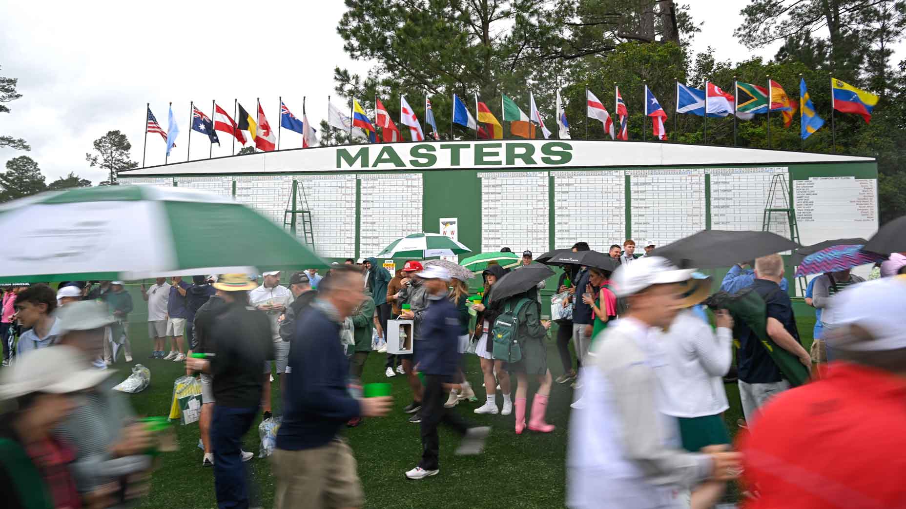 patrons walk in front of the scoreboard during monday practice rounds of the 2025 masters tournament