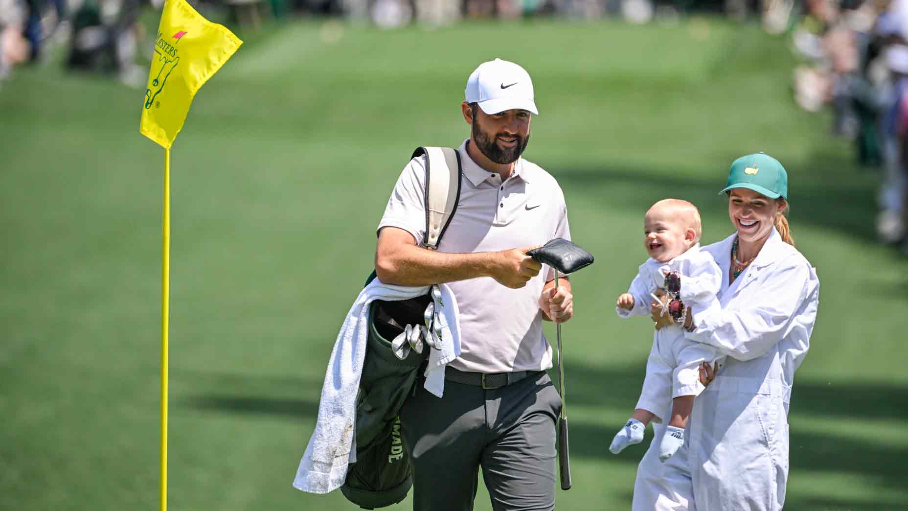 Scottie Scheffler and his wife Meredith Scheffler smile with their son Bennett during the Par Three Contest prior to the Masters Tournament at Augusta National Golf Club on April 9, 2025 in Augusta, Georgia