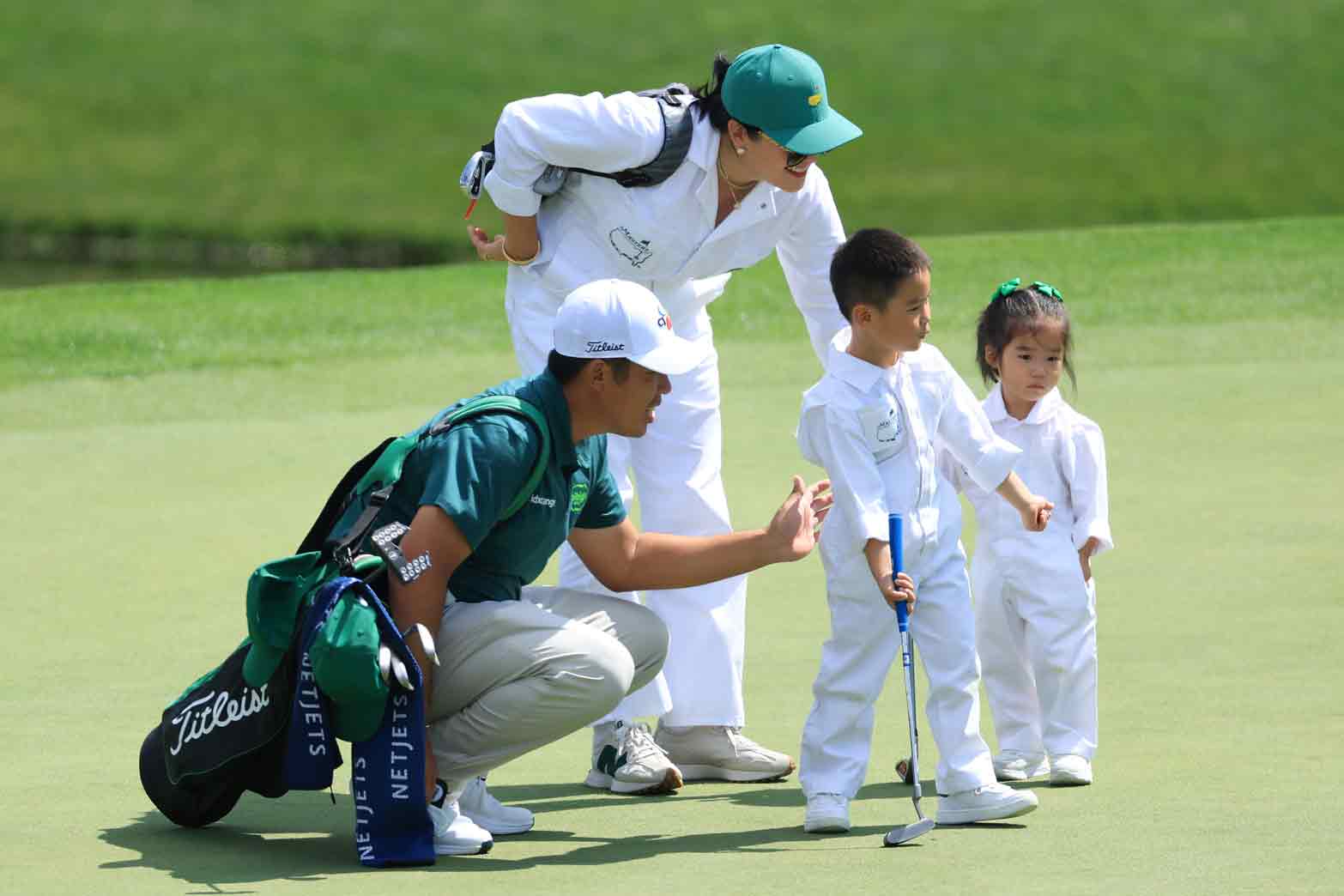 Byeong Hun An of Korea lines up a putt with wife Jamie & children An Sun-woo & An Ji-woo during the Par Three Contest prior to the 2025 Masters Tournament at Augusta National Golf Club on April 9, 2025 in Augusta, Georgia.