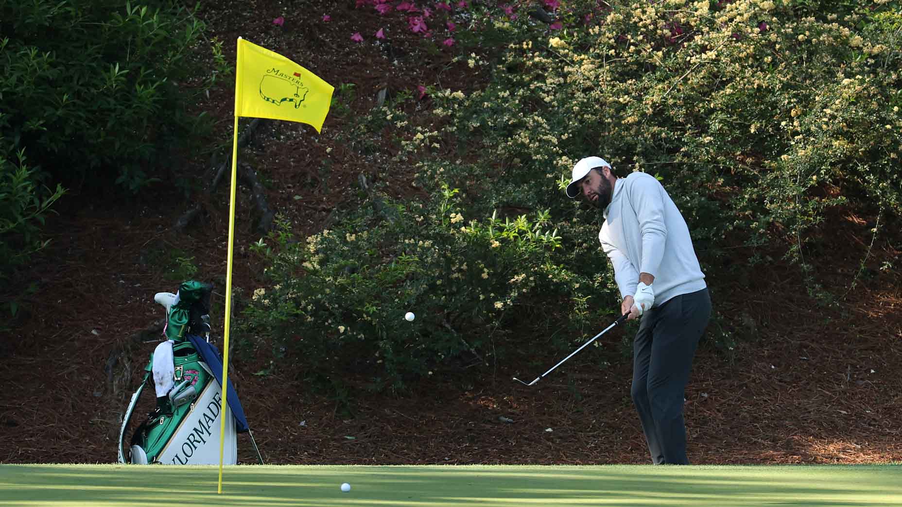 scottie scheffler hits a chip shot on the 12th hole at augusta national ahead of the 2025 masters
