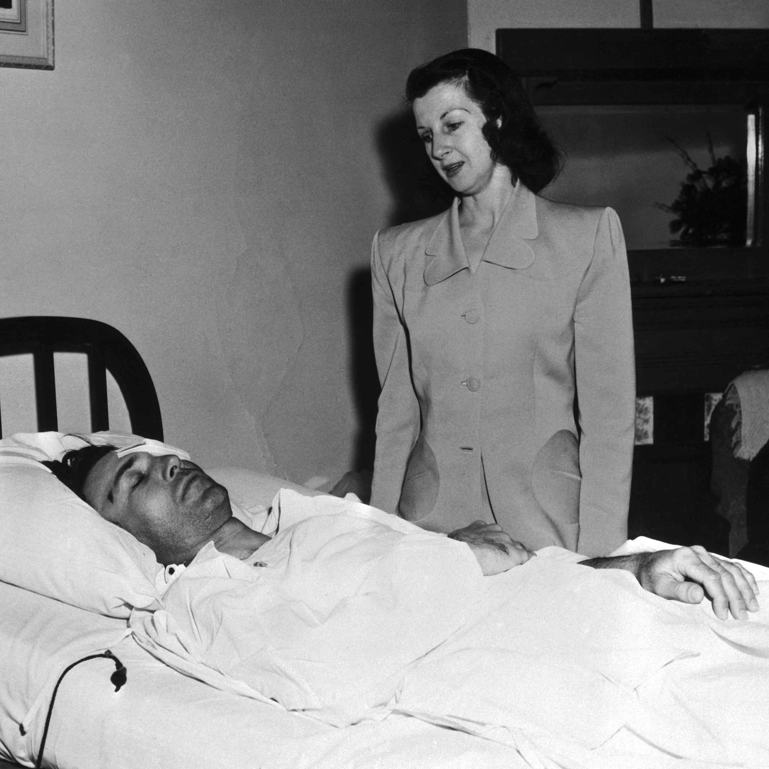 Mrs. Valerie Hogan stands at the bedside of her husband, pro golfer Ben Hogan, as he rests in his hospital bed at El Paso