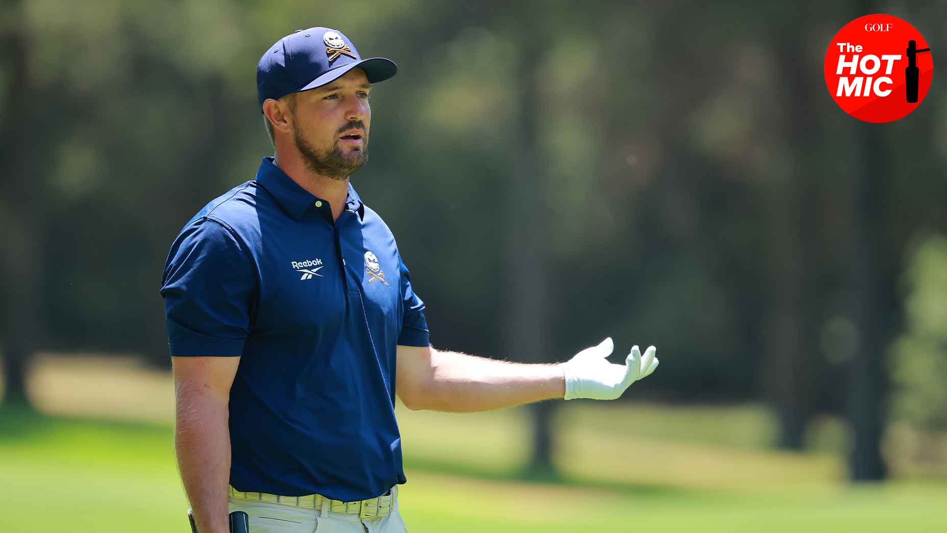 bryson dechambeau holds up hand at LIV Mexico event in navy shirt and navy hat