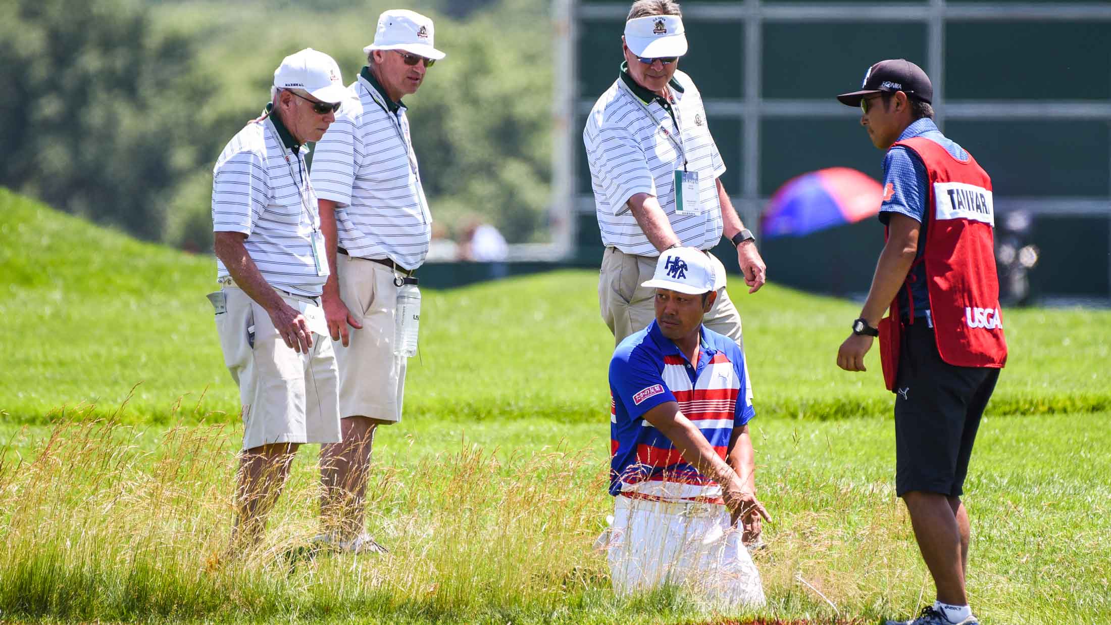 Hideto Tanihara of Japan looks for his ball in a hazard / ditch on the 18th hole fairway during the continuation of the second round of the U.S. Open at Oakmont Country Club