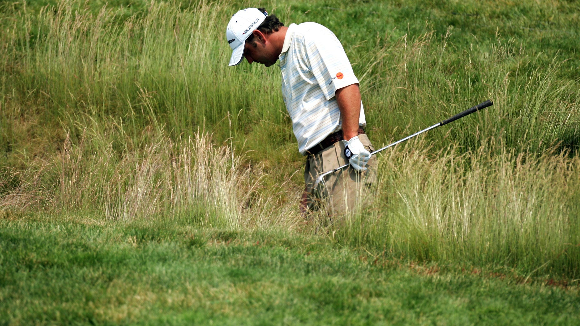 A player hunting for a ball in the rough at Oakmont