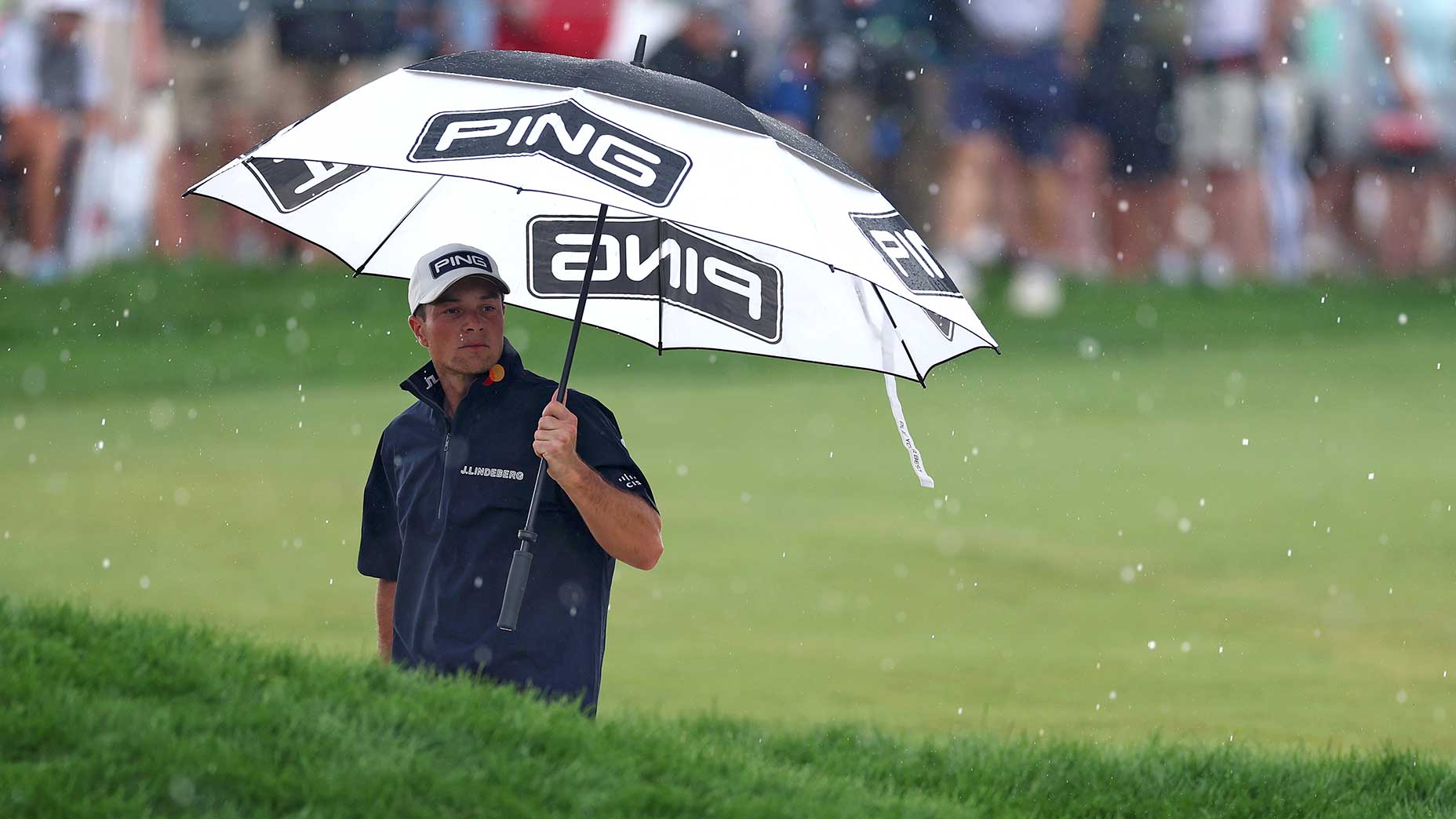 Viktor Hovland takes cover under an umbrella during the final around of the 2025 U.S. Open on Sunday at Oakmont Country Club.