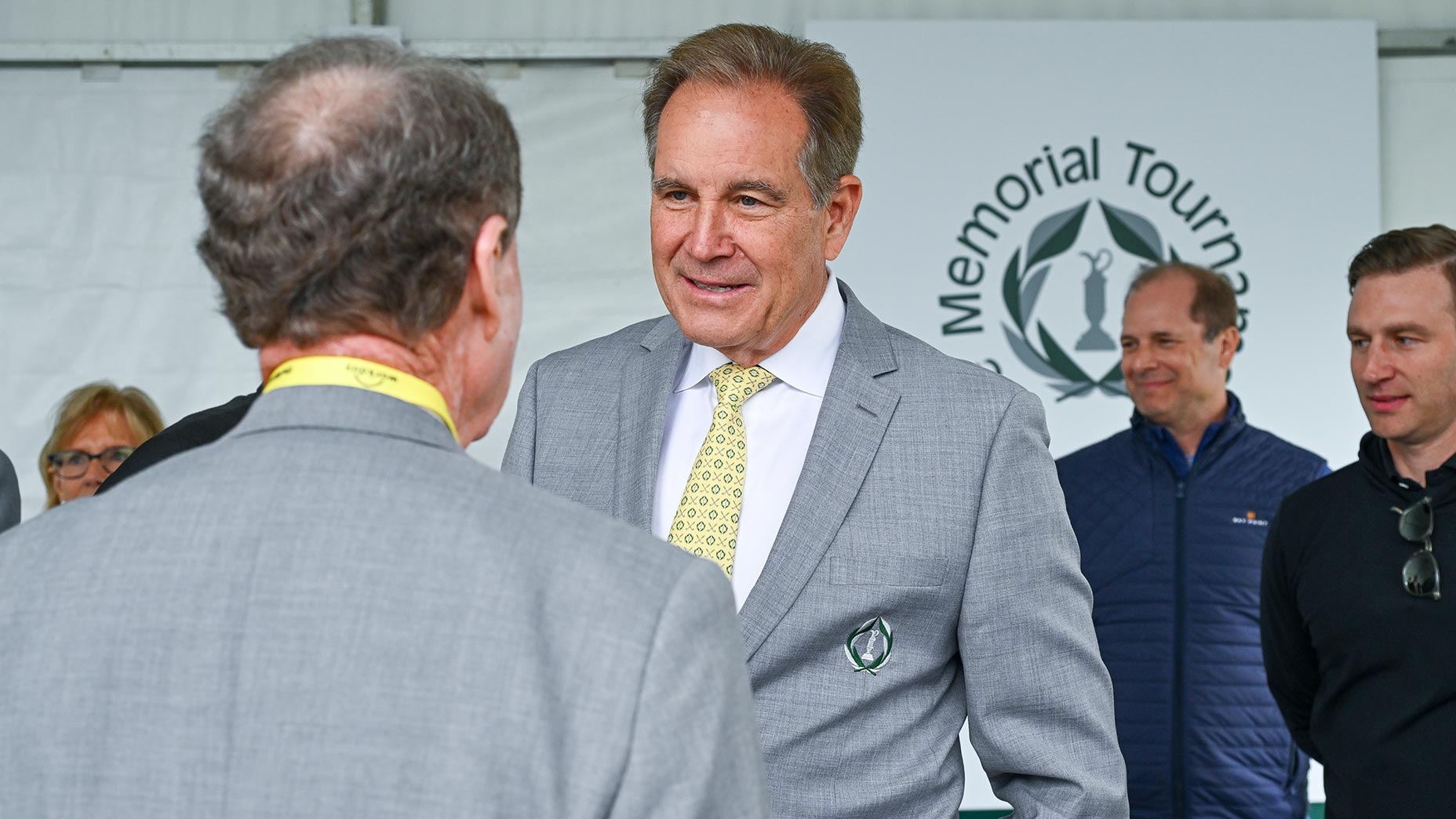 jim nantz smiles at the memorial tournament in gray suit