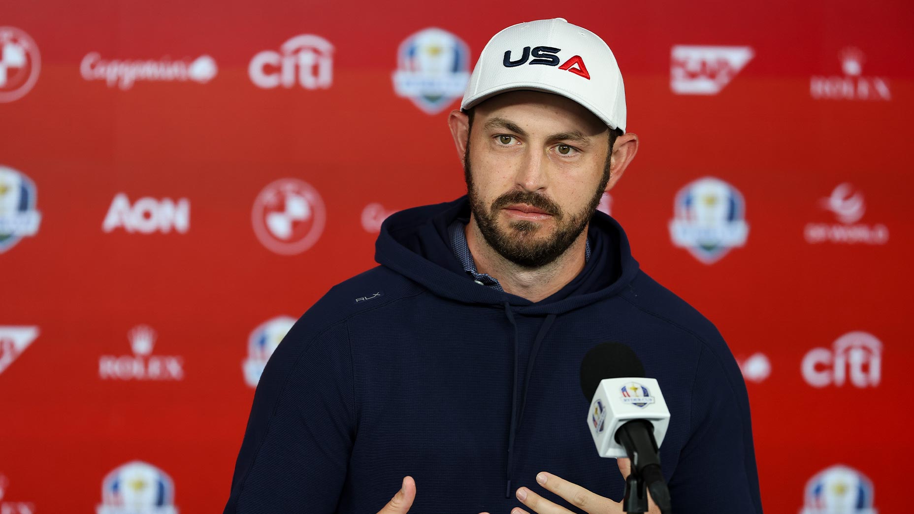 patrick cantlay speaks at the ryder cup wearing usa hat