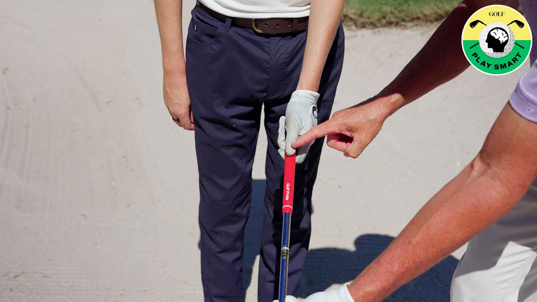 hand with golf glove holds club with red grip