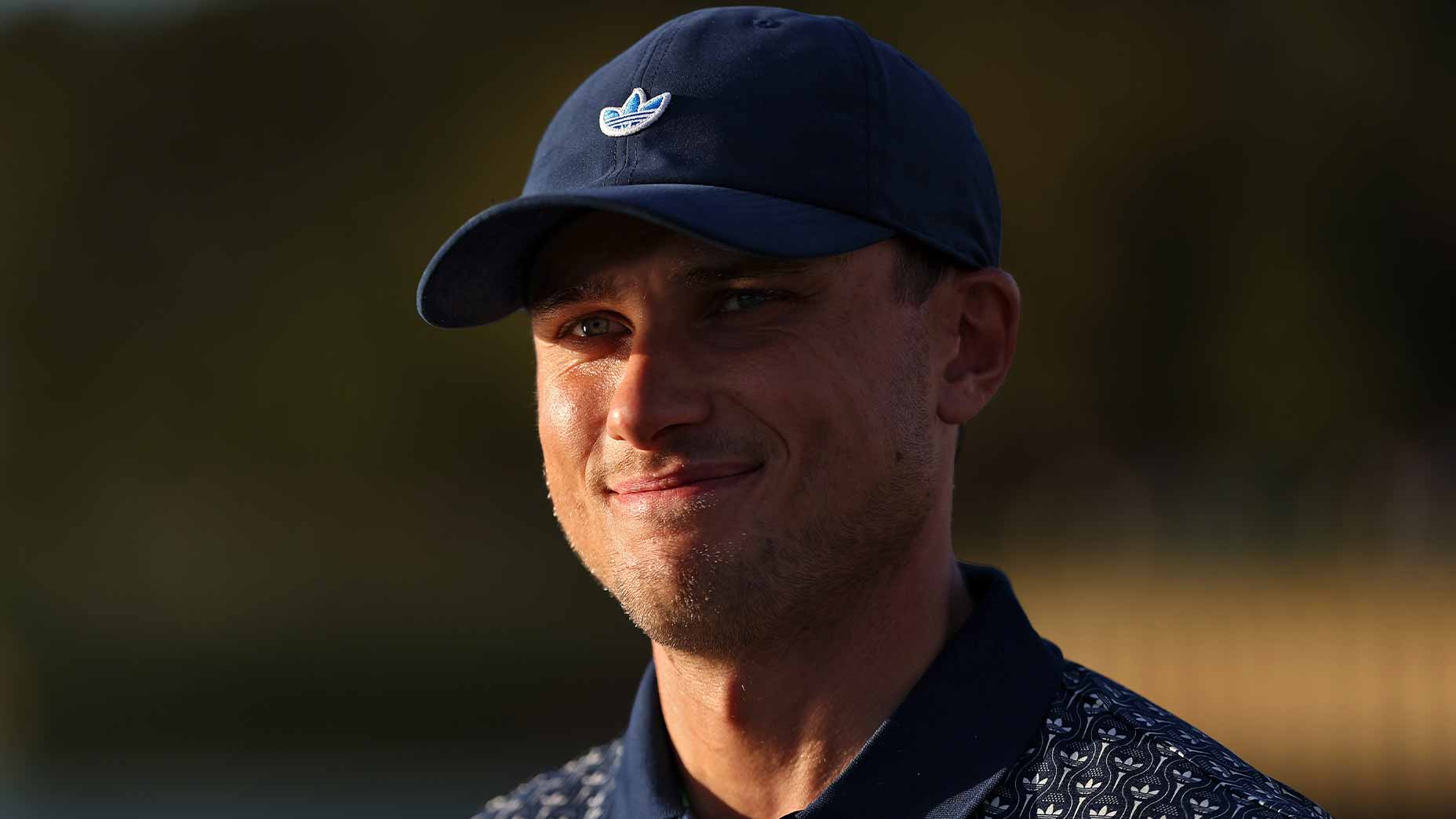ludvig aberg smiles at the players championship in a navy hat and navy hsirt