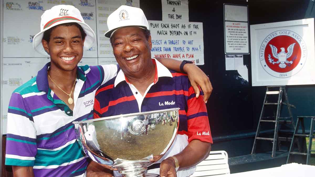 Tiger Woods, age 15 years, six months, and 28 days, and father Earl Woods, pose for a photo while celebrating Tiger's victory at the 1991 USGA Junior Amateur Championship