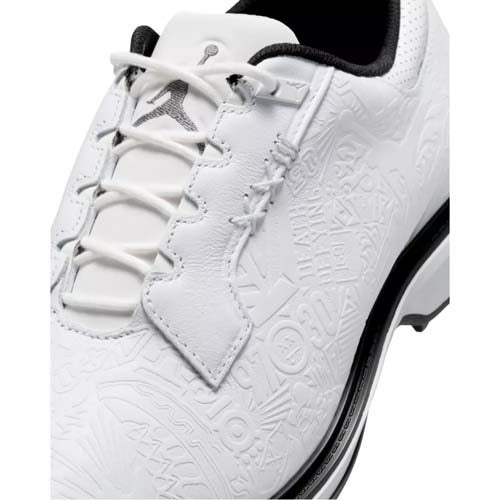 Close-up of a white sneaker with embossed patterns, white laces, and a black Jumpman logo on the tongue. The shoe features a black trim along the sole and a textured leather upper, making it one of the best Jordan golf shoes for style and performance.