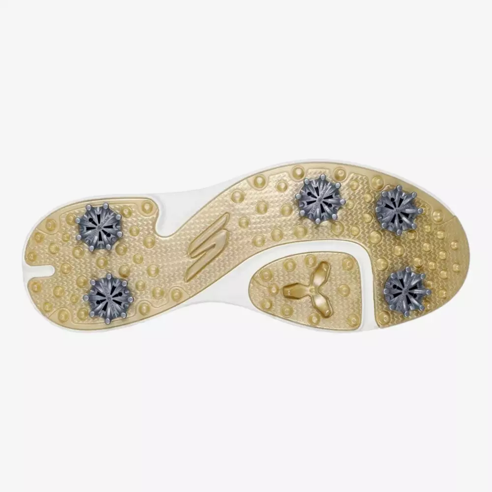 The image shows the sole of one of the best women's golf shoes 2026, featuring four silver spikes and a gold and white textured surface, designed for excellent grip and stability on the course.
