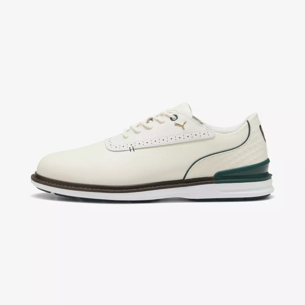 A white leather golf shoe with a brown sole, green accents on the heel and collar, white laces, and a small gold Puma logo on the side—perfect for those seeking style and comfort like the best Jordan golf shoes.